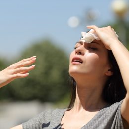 Stressed woman drying sweat with a cloth in a warm summer day.