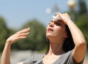 Stressed woman drying sweat with a cloth in a warm summer day.