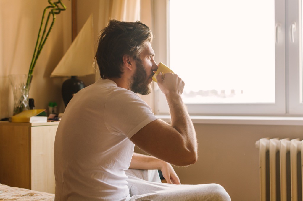 man drinking coffee in bed