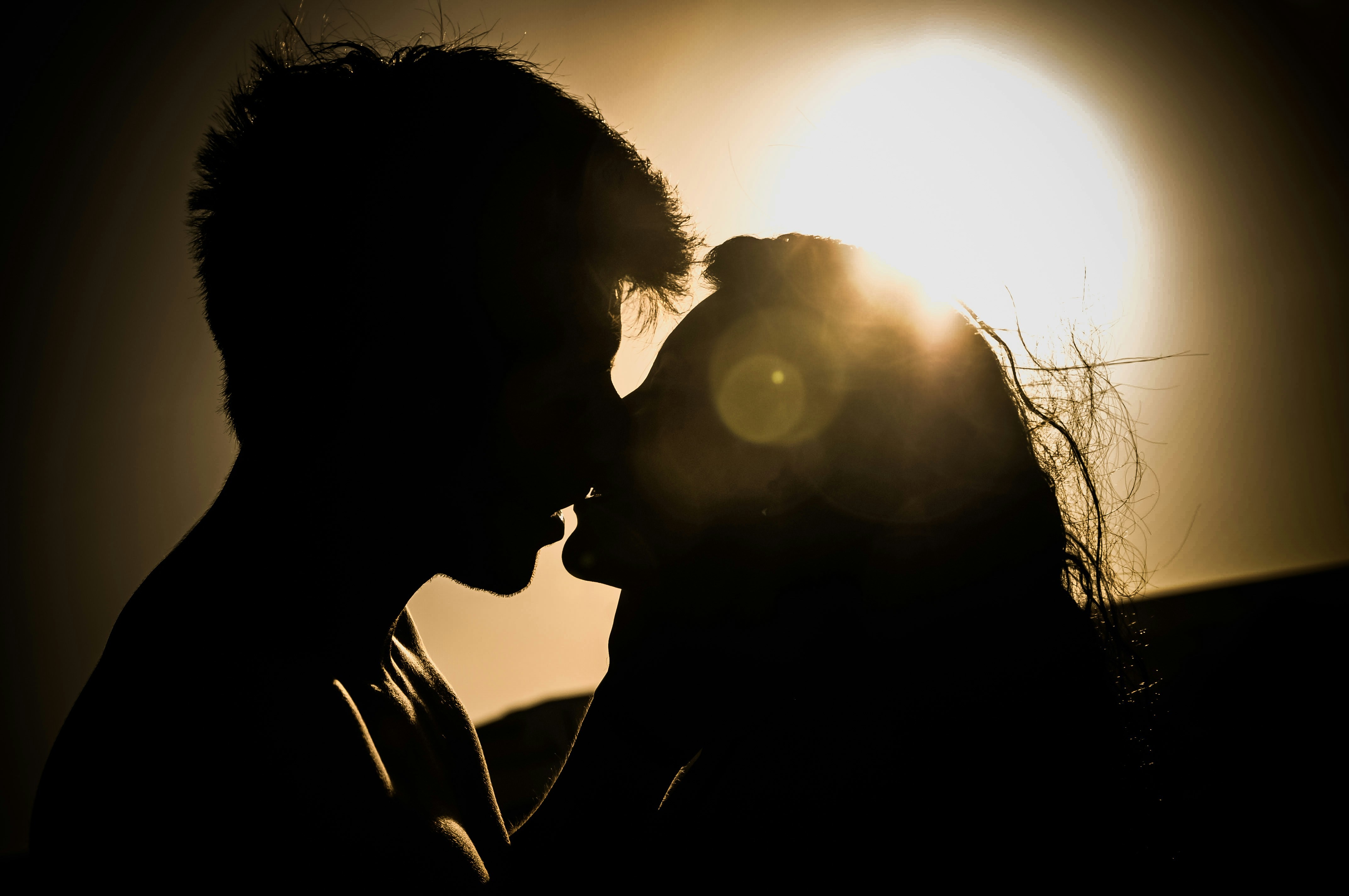 couple kisses with the sun behind them