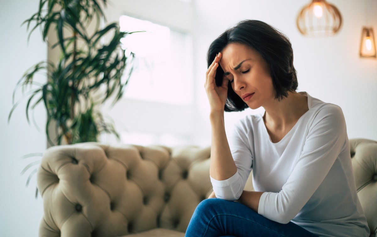 Woman with headache sitting on couch