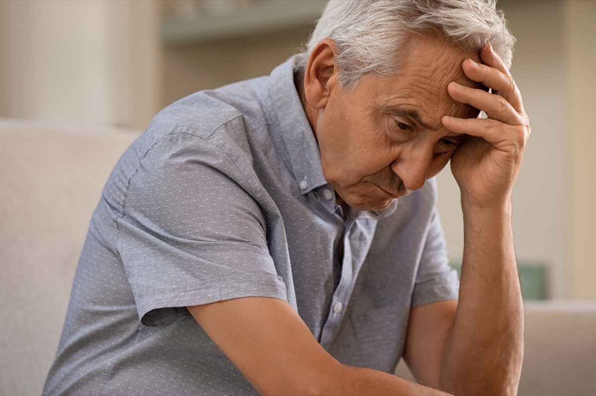 mature man sitting with his hand on his head while looking away