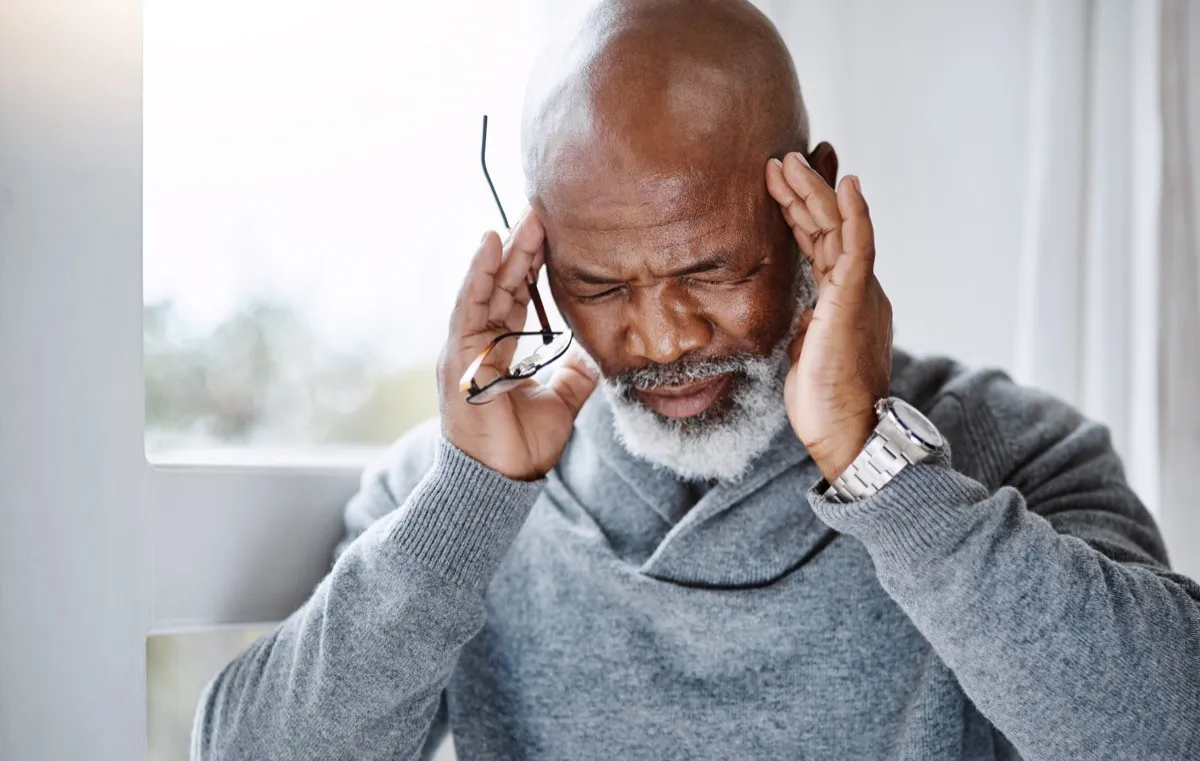 Shot of a handsome senior man suffering with a headache at home and looking stressed out