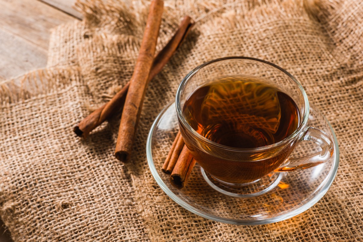 a cup of cinnamon tea with cinnamon sticks on burlap