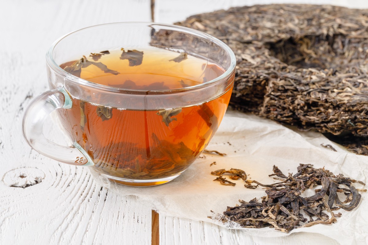 A cup of Pu-erh tea is next to a large piece of puer