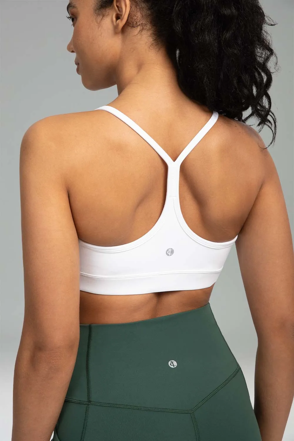 closeup back view of a woman wearing a white sports bra and green leggings