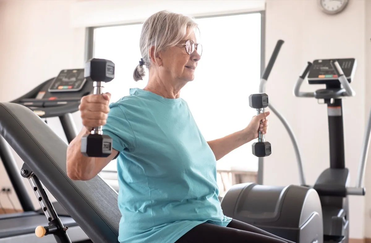older woman lifting weights at the gym