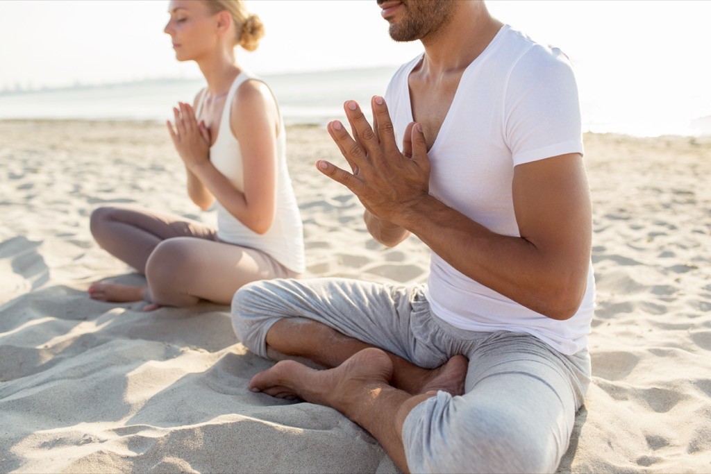 Couple meditating on the beach.