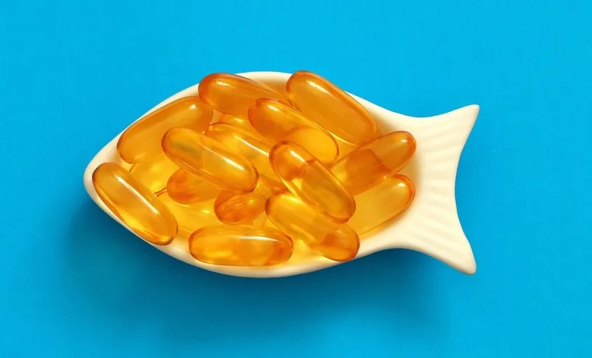 fish oil capsules in a fish-shaped bowl on a blue background