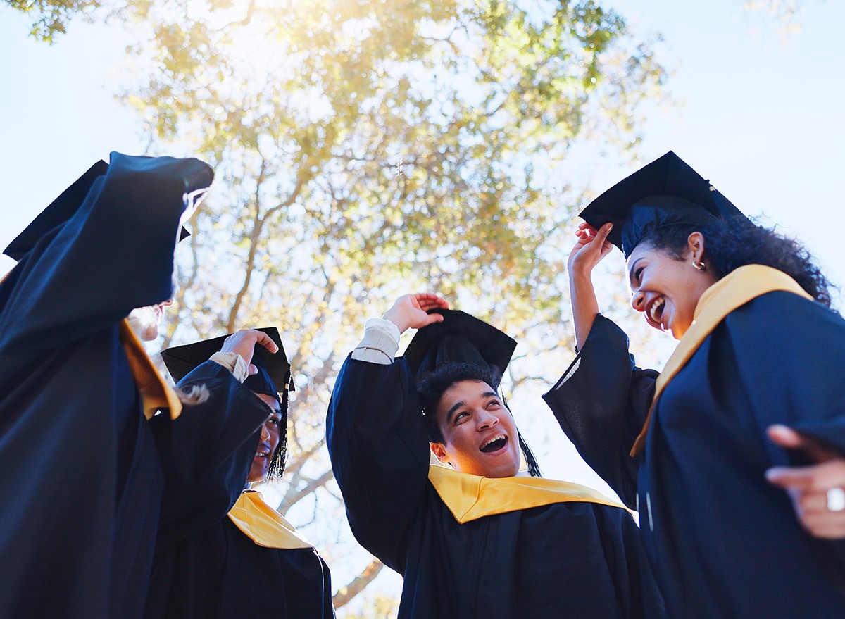 Happy students wearing college graduation caps and gowns.