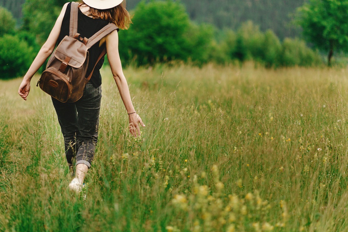 Woman walking through a field of grass.