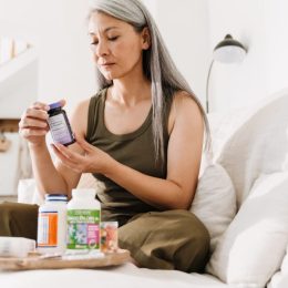 woman sitting on bed reading supplement bottle