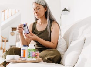 woman sitting on bed reading supplement bottle
