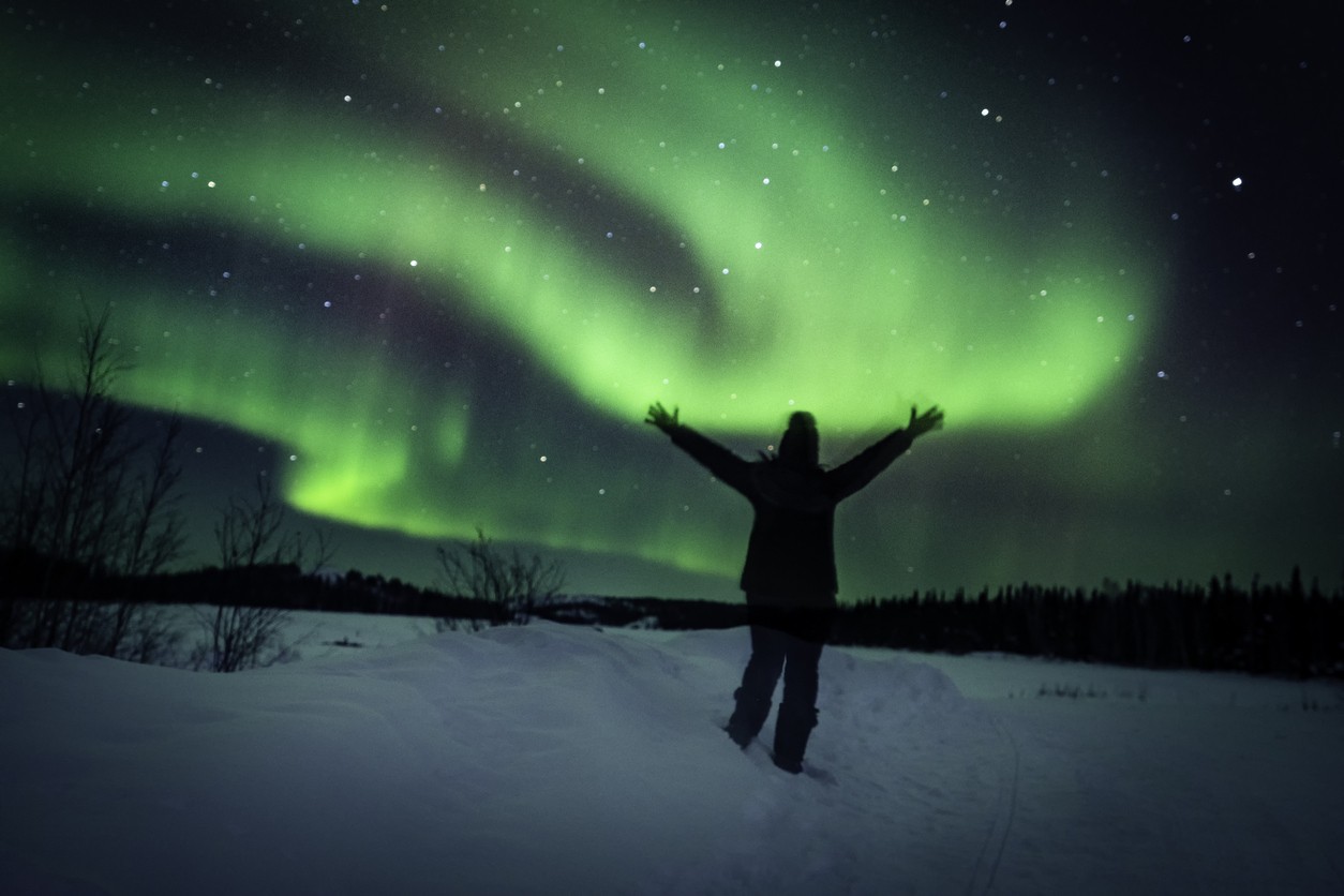 A person watching the Northern Lights in the snow.