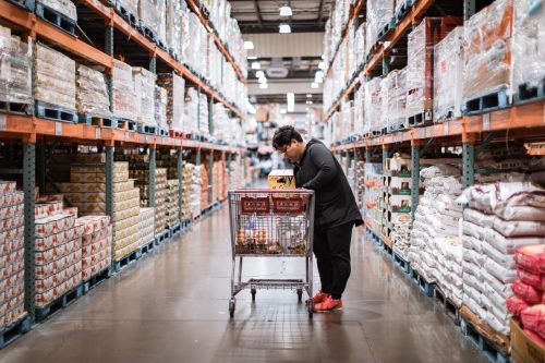 woman loading her shopping cart in a Costco aisle
