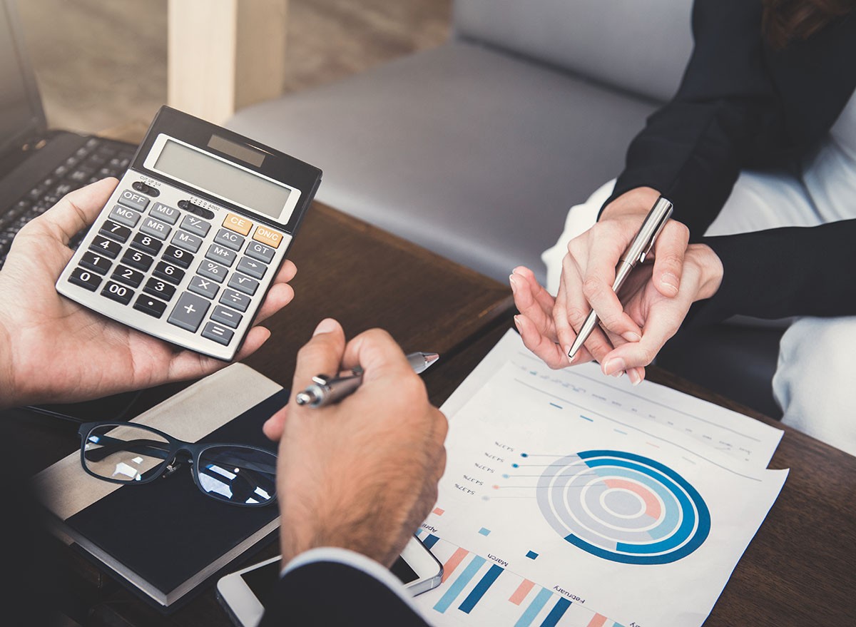 A meeting with two people, looking over charts and graphs.