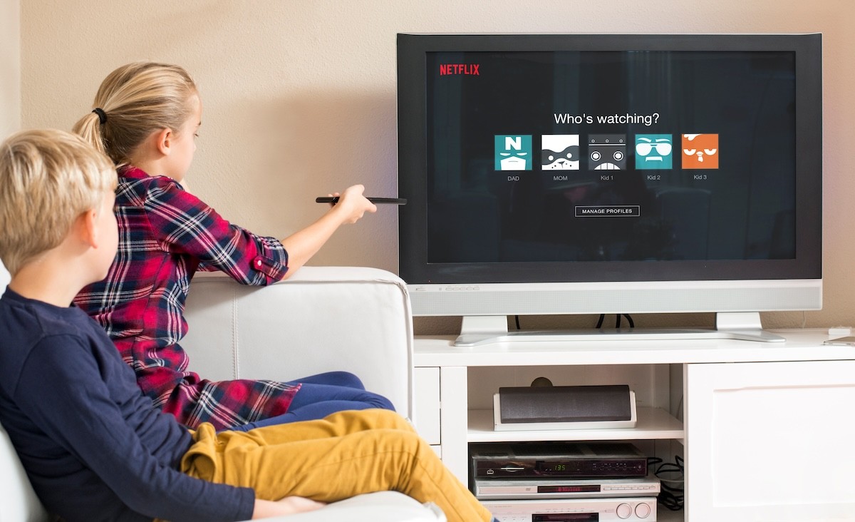 two children sitting on the couch, selecting their user icon for Netflix on the TV