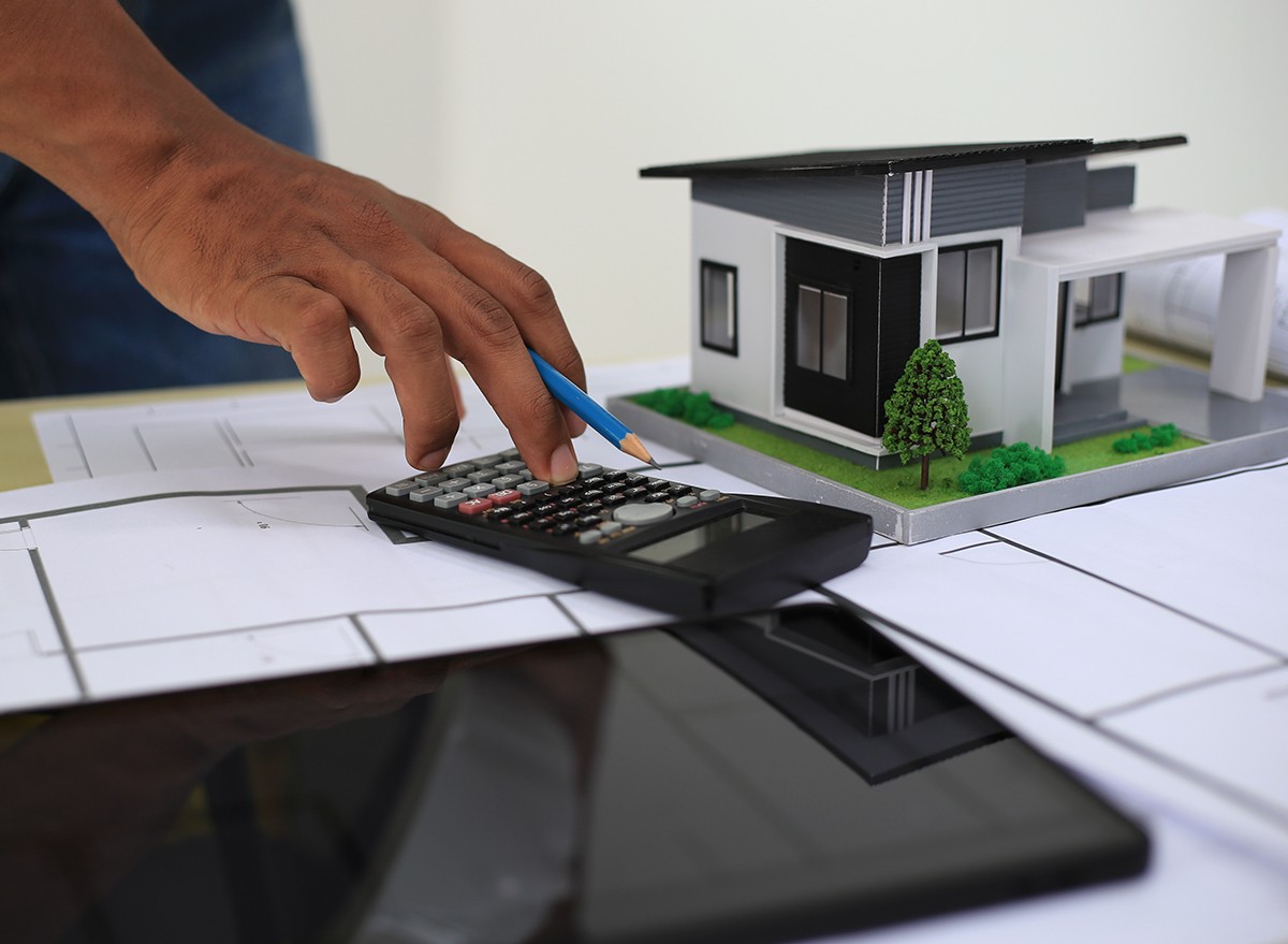 Architect and designer using blueprints and laptop to draw building structure in office