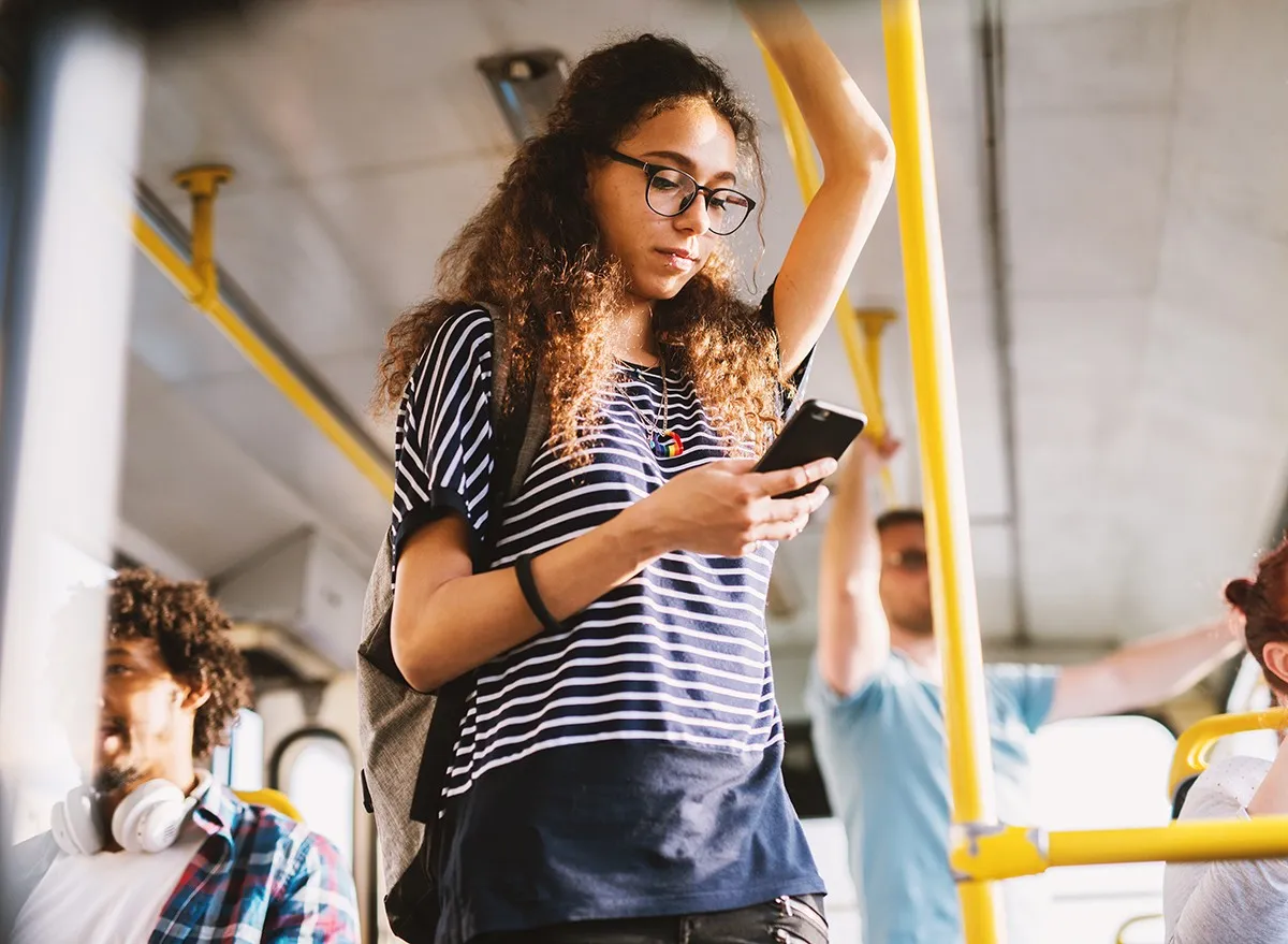 Woman on public transit looking at text messages on her phone