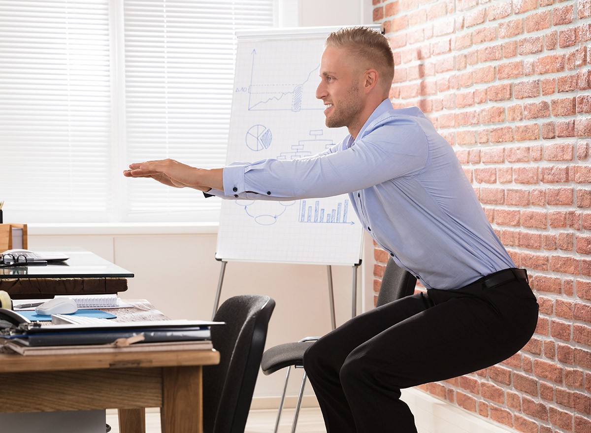 Man takes a break from work at his desk to do squats