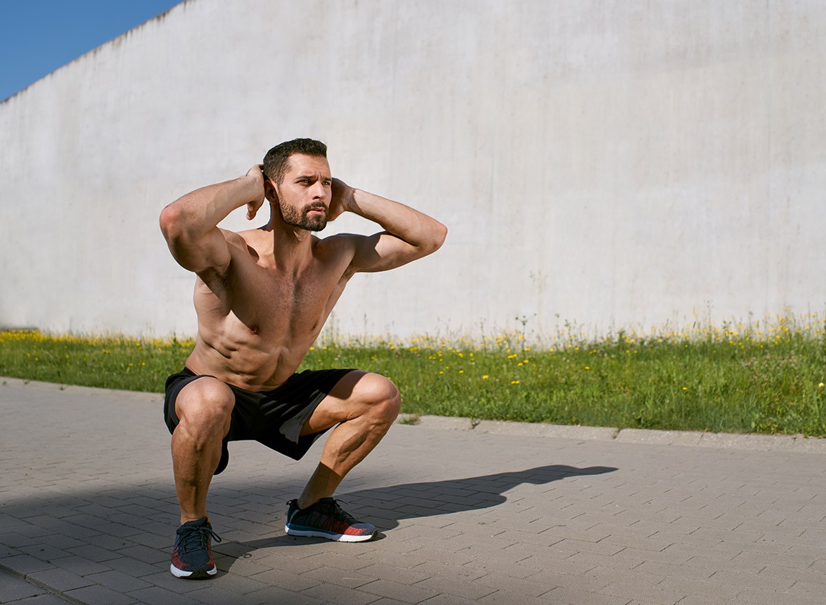 An athletic man doing squats outside