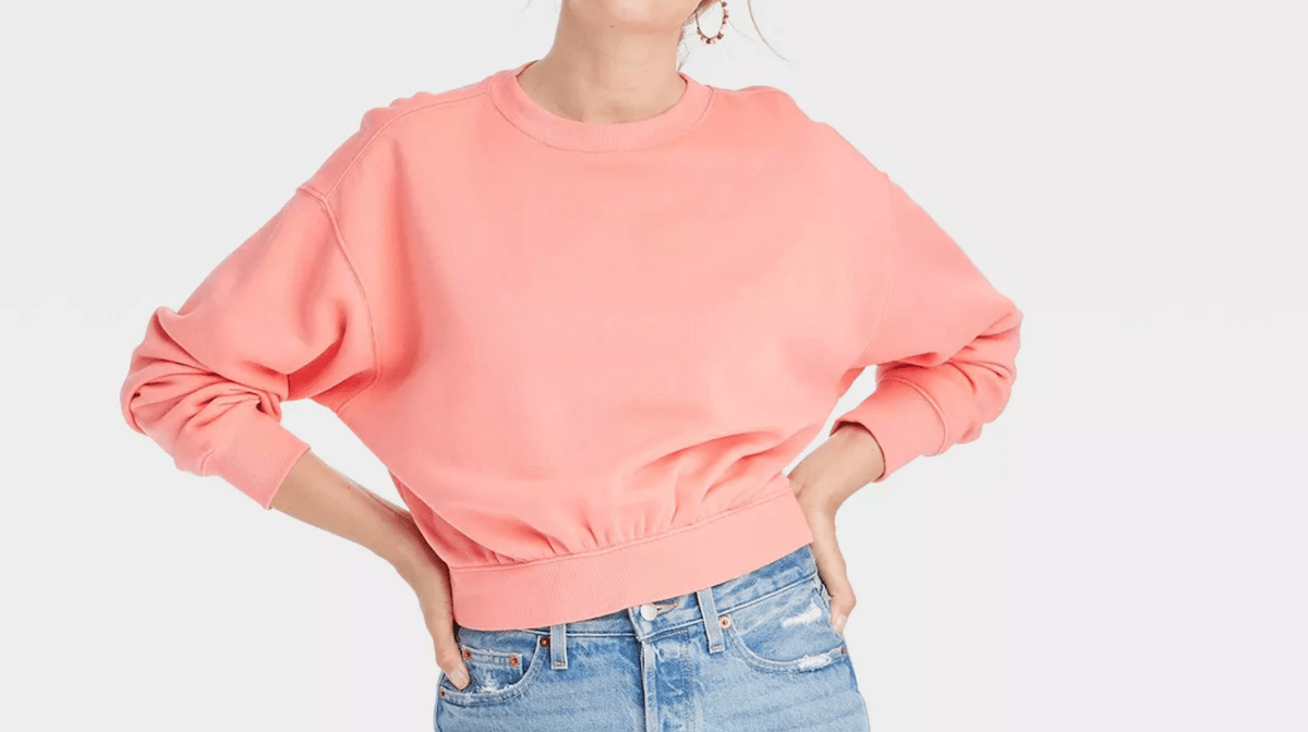 cropped image of a woman wearing a peach sweatshirt and jeans
