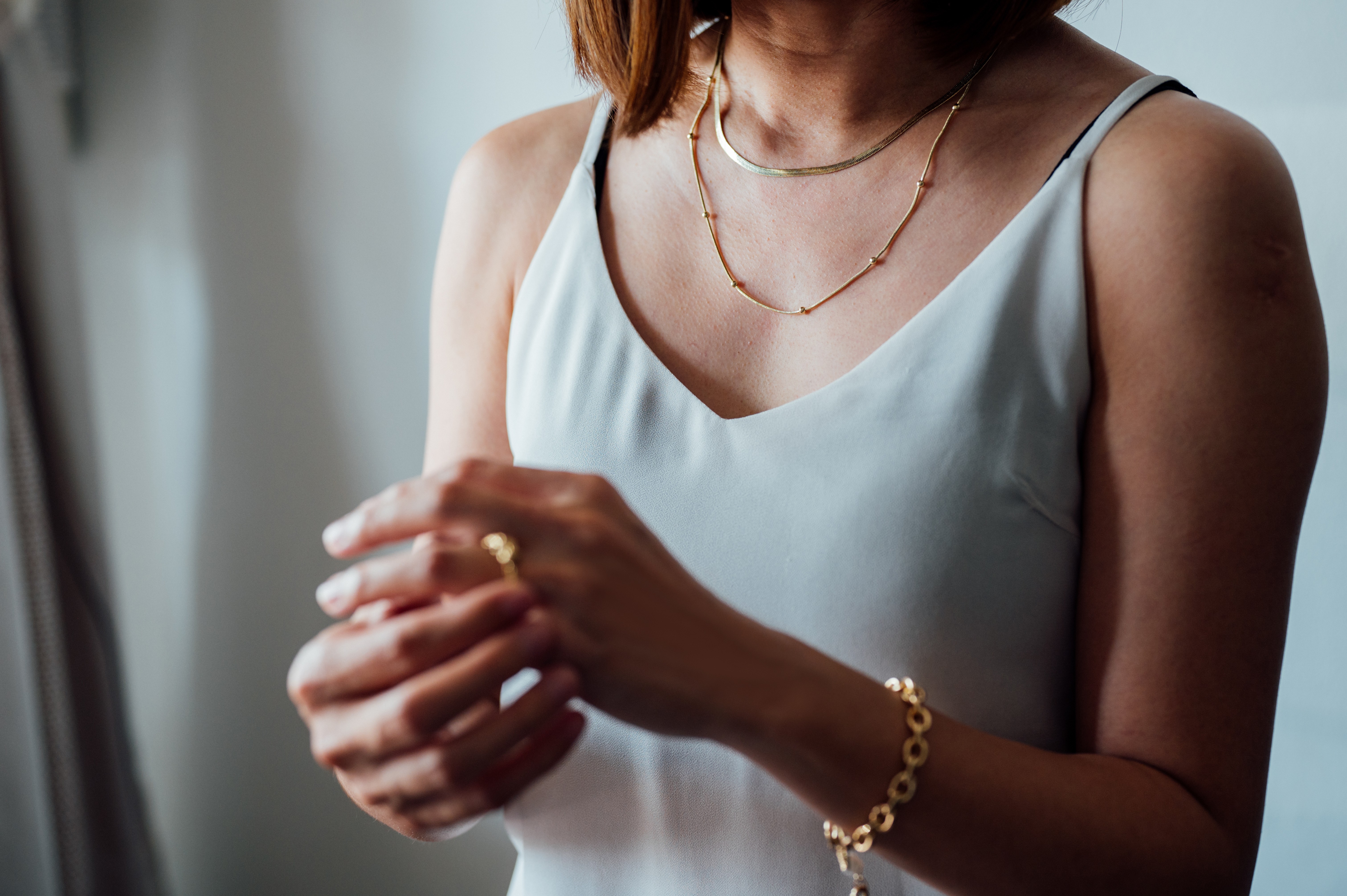 Close-up portrait of a woman wearing gold ring, necklace and bracelet.