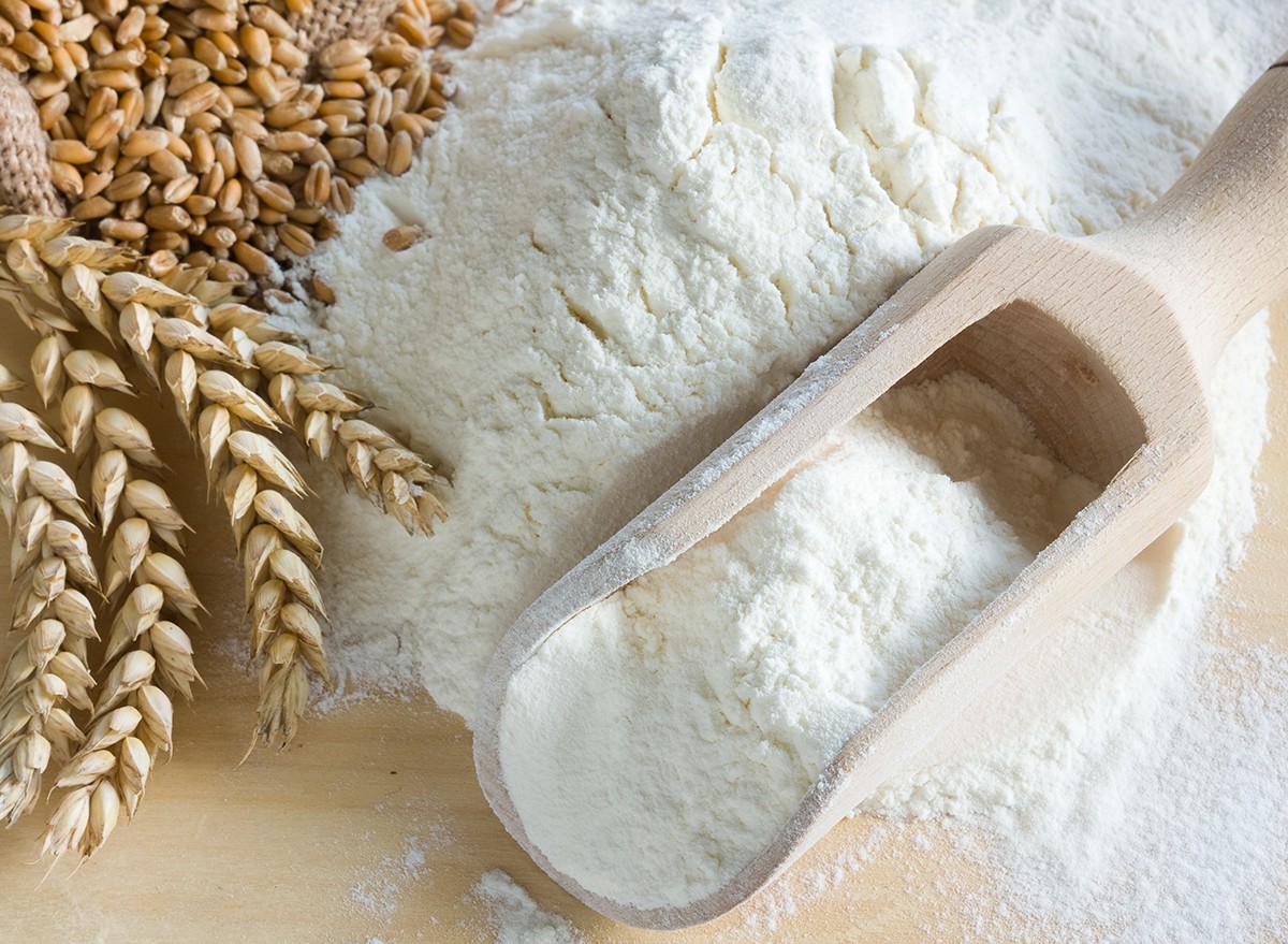 White flour and wheat grain on a wooden surface