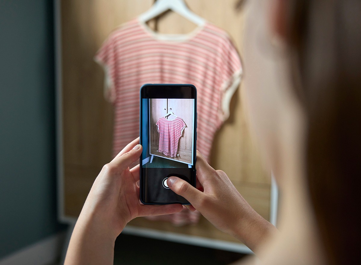 A woman photographs a pink top that she will sell online