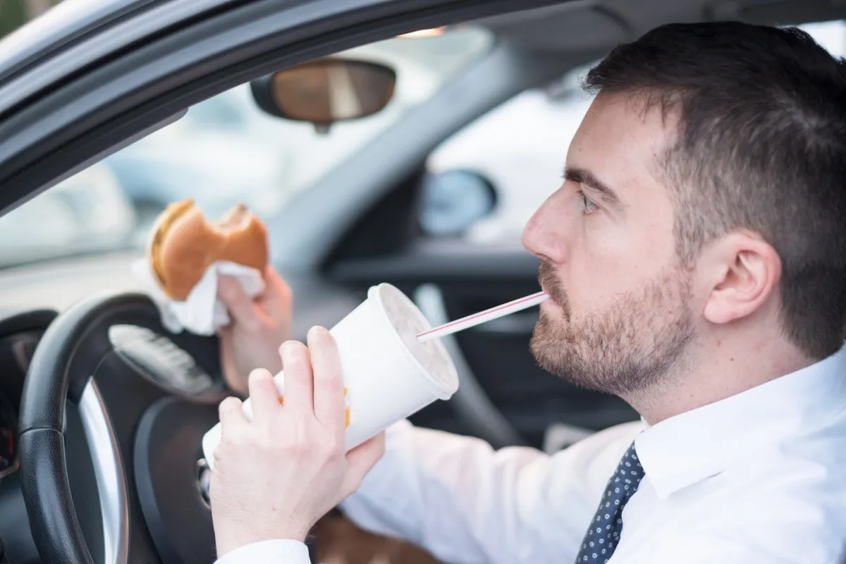 30 something man eating fast food in car
