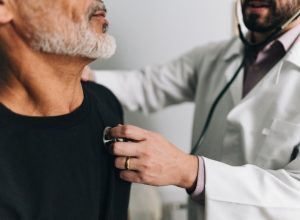 male doctor testing the heart beat of a male patient