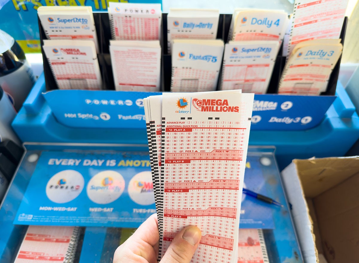 A man's hand holding Mega Millions Lottery blank tickets