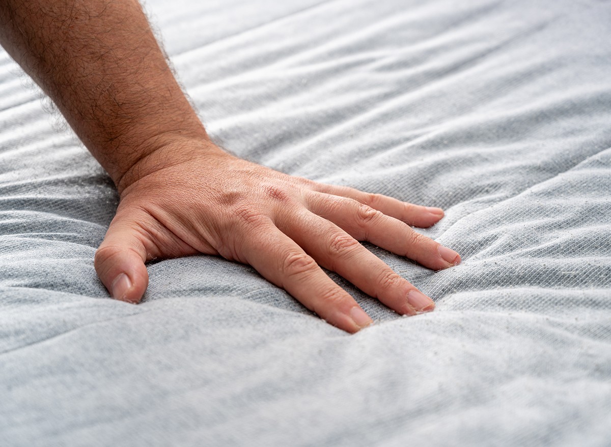 A man's hand testing the feel of a mattress
