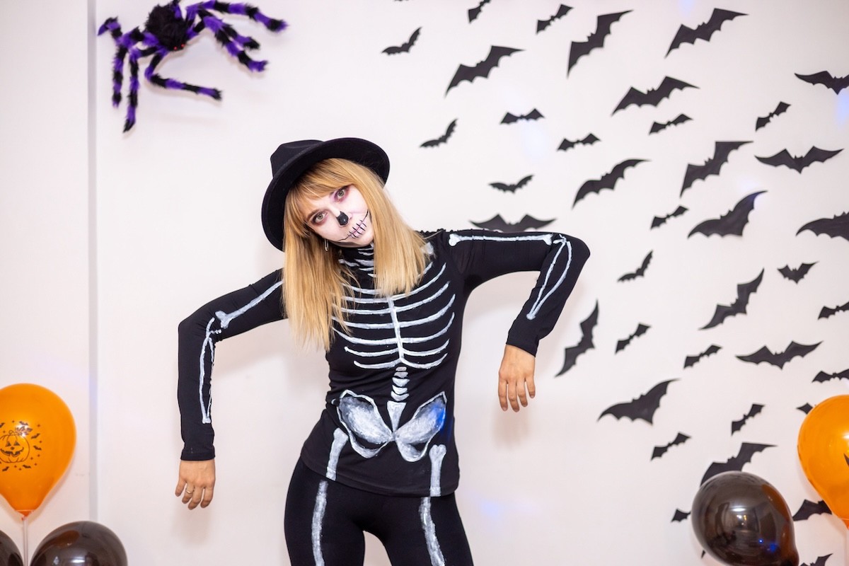woman in a skeleton costume, posing in front of Halloween decorations