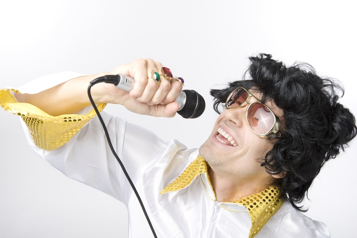 man dressed in Elvis costume, singing into a mic
