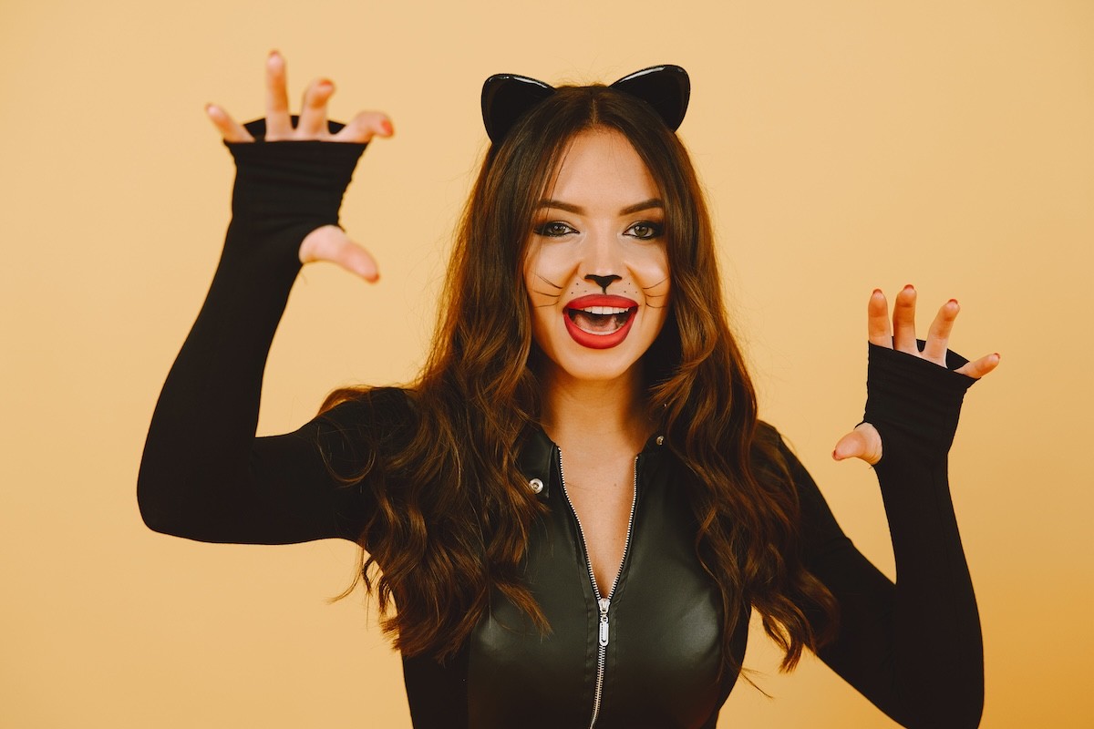 woman dressed in black cat costume against an orange background