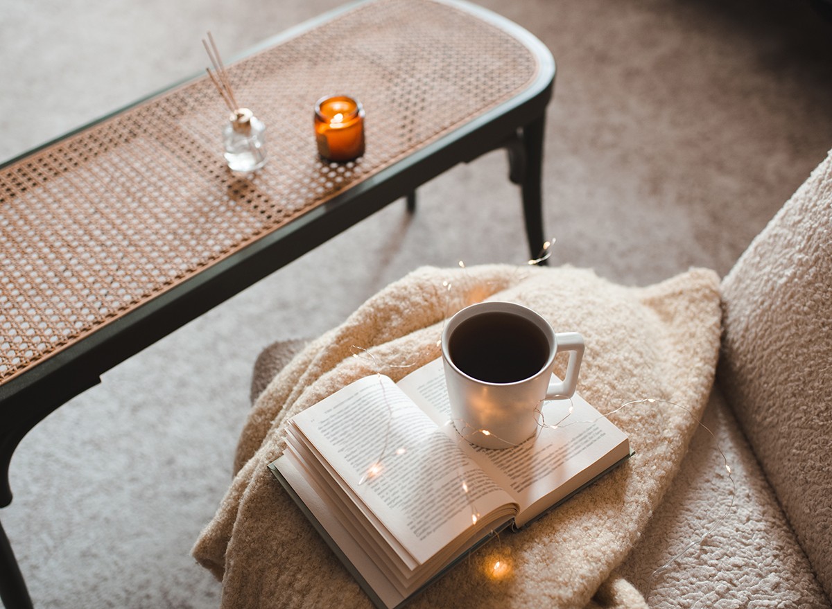 A cozy reading corner with book, coffee and soft blanket