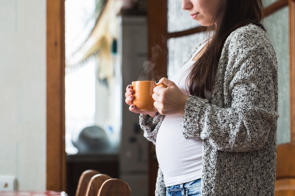 A pregnant woman drinking a hot drink