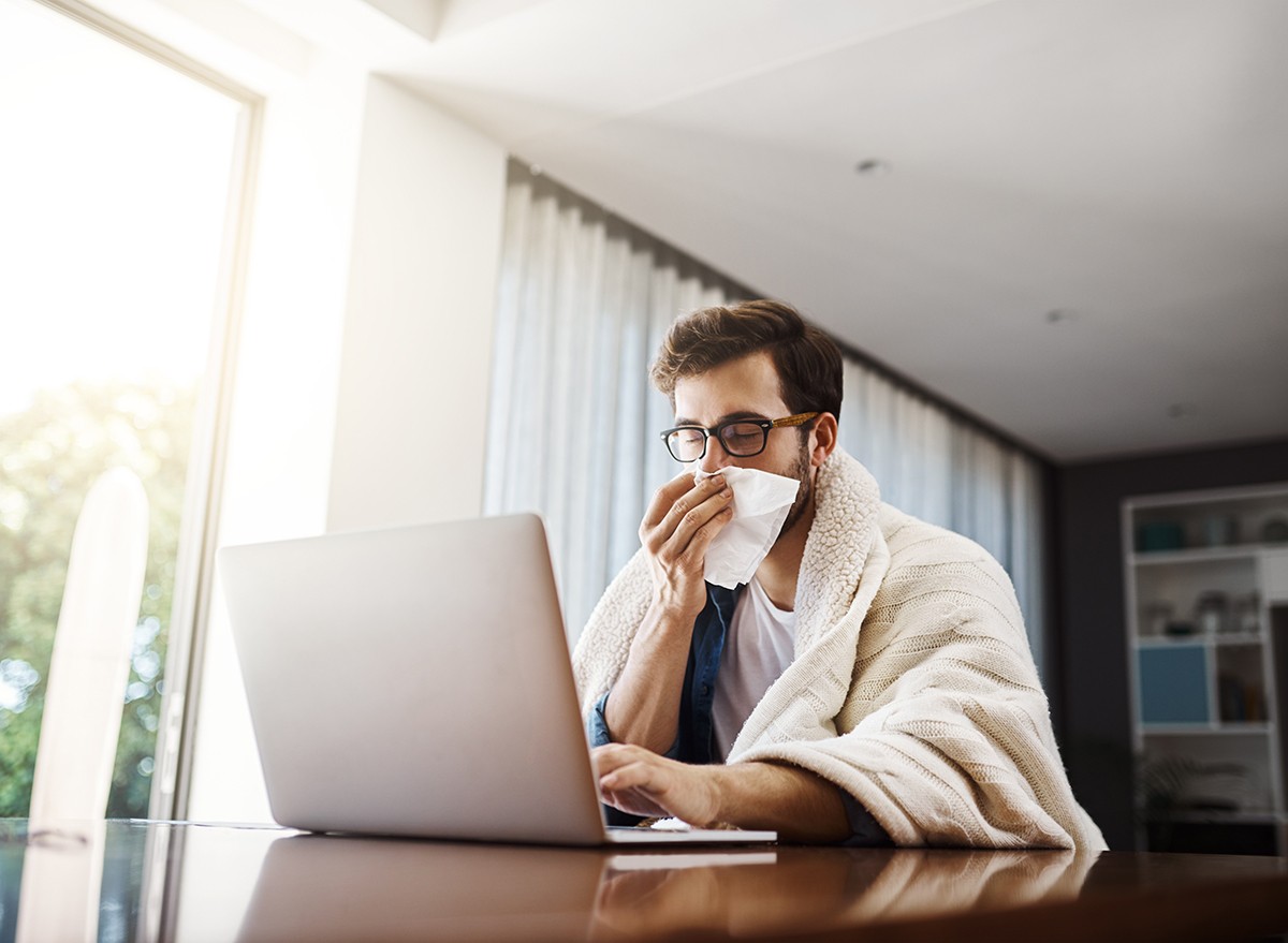 A man suffering with allergies works on a laptop