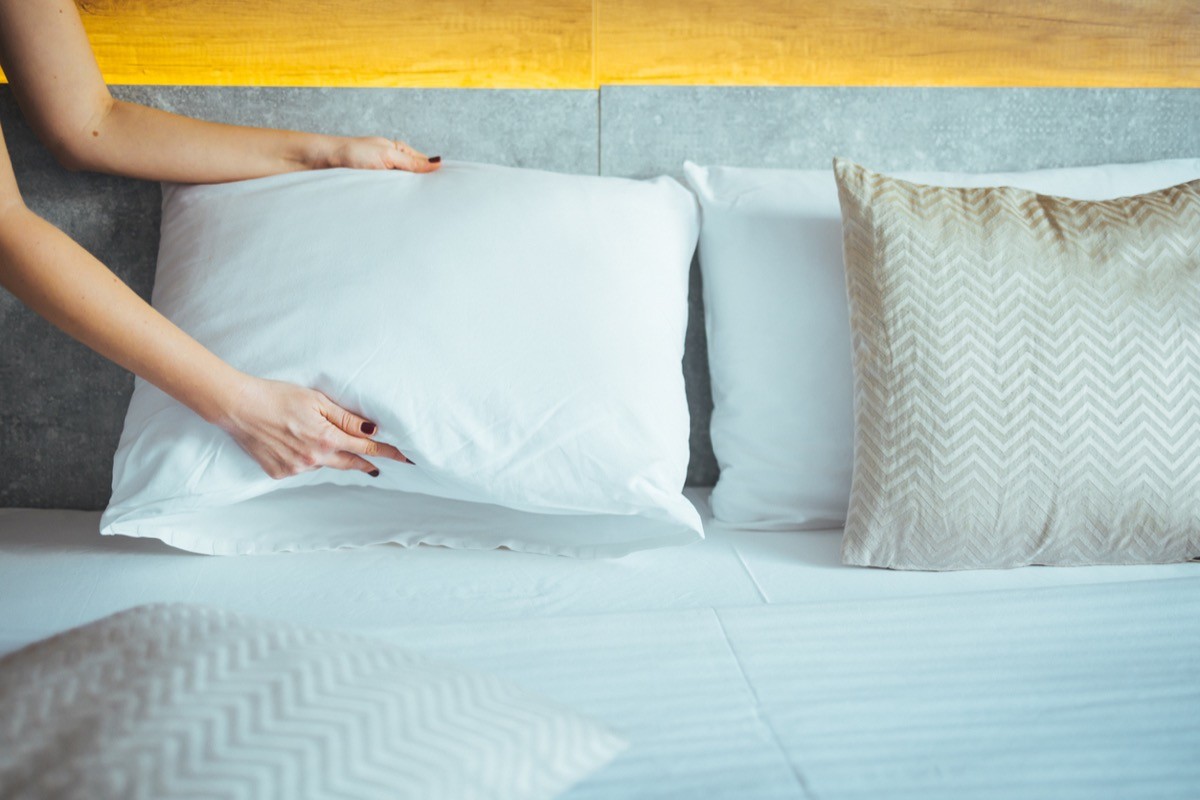 Female hands fluffing the pillows on a bed