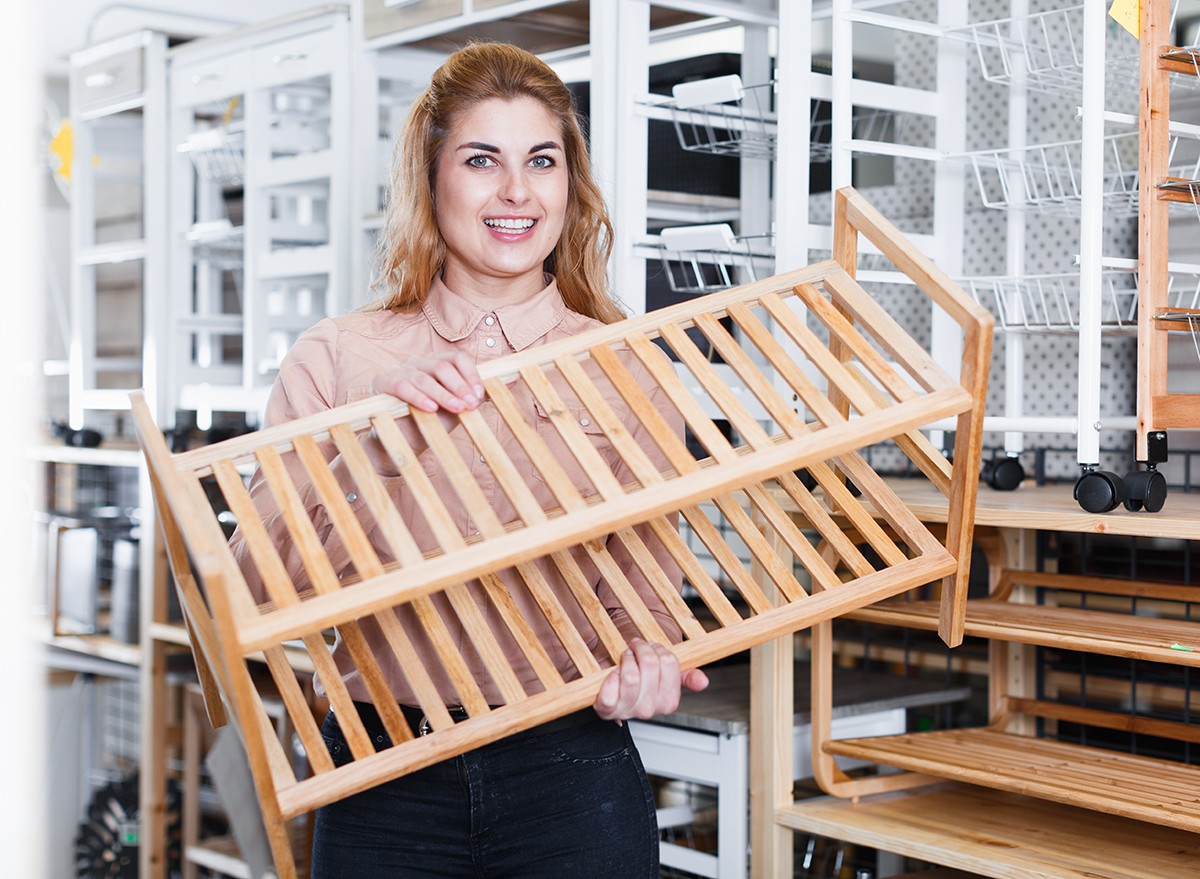 A woman holding a stackable bamboo shoe rack