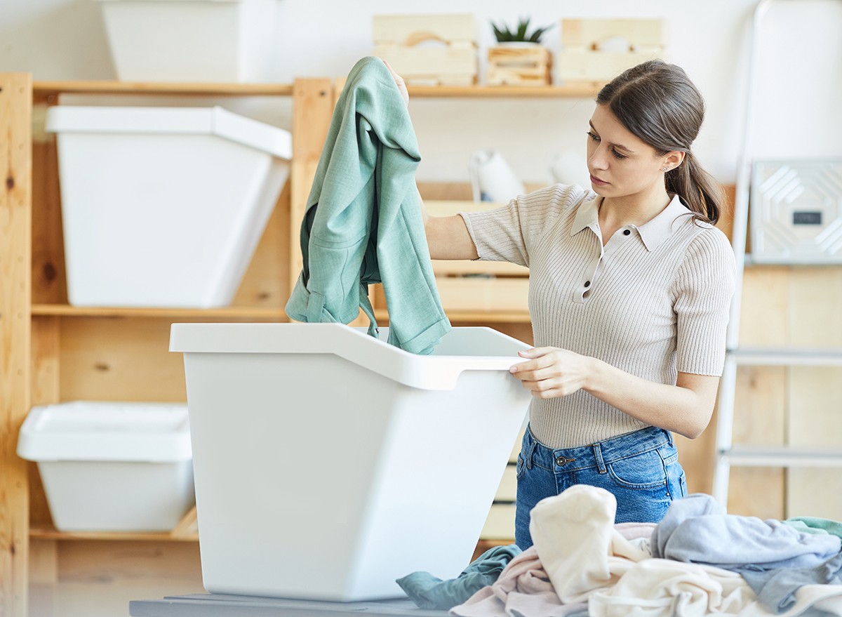 A woman sorts clothing into bins in a closet