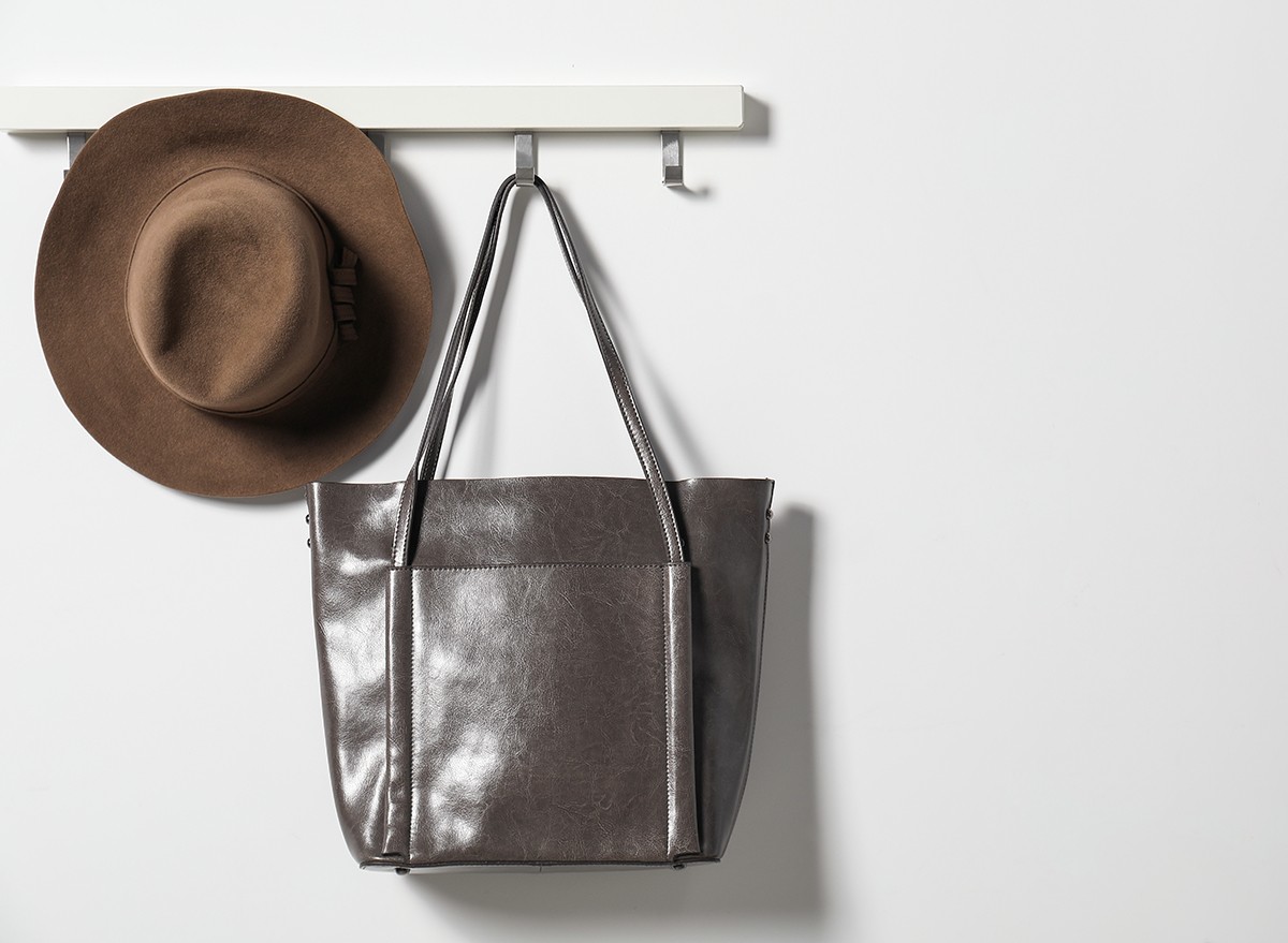 Wall hooks in a closet holding a hat and purse