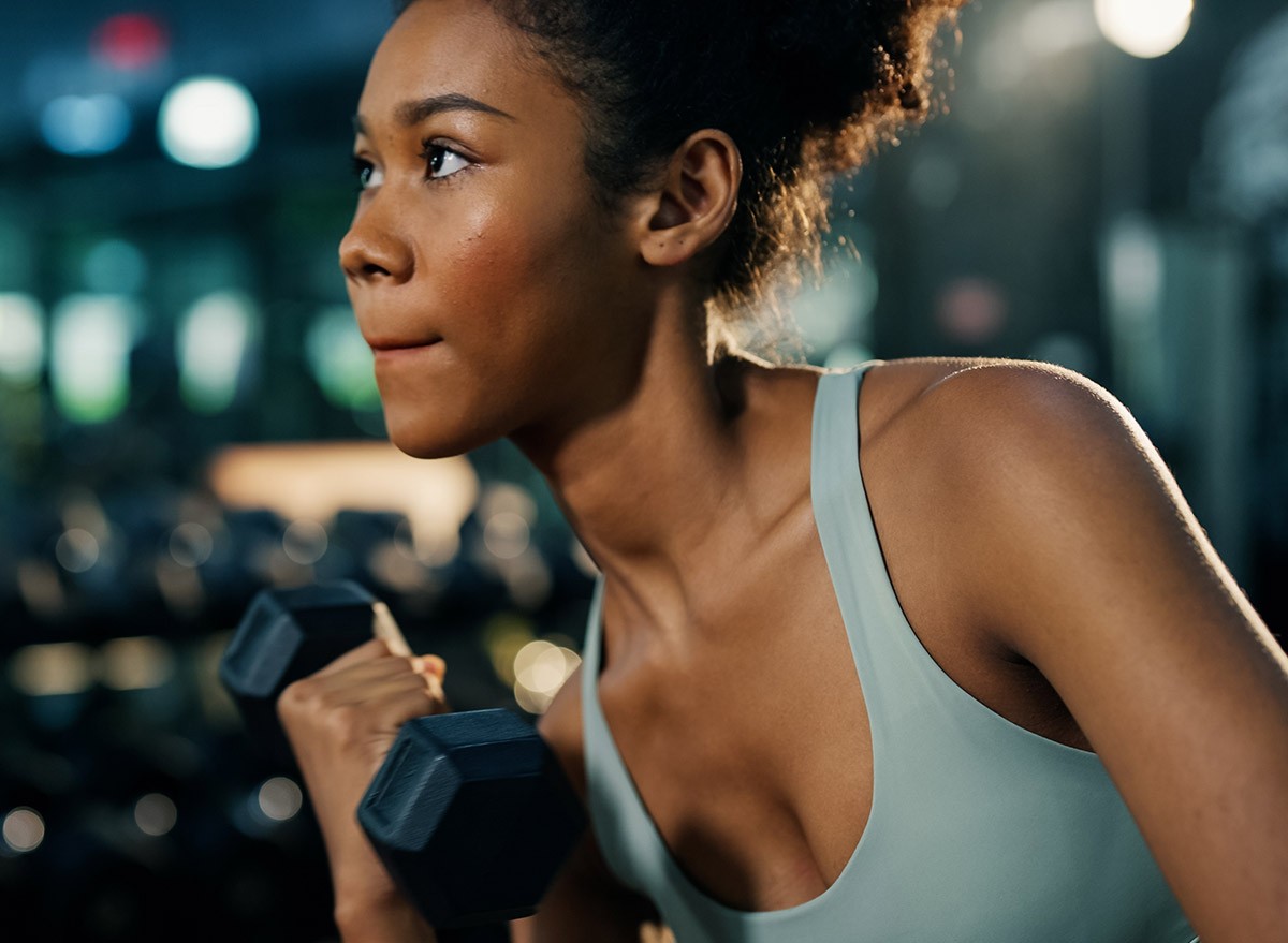 A woman lifts weights at the gym. 