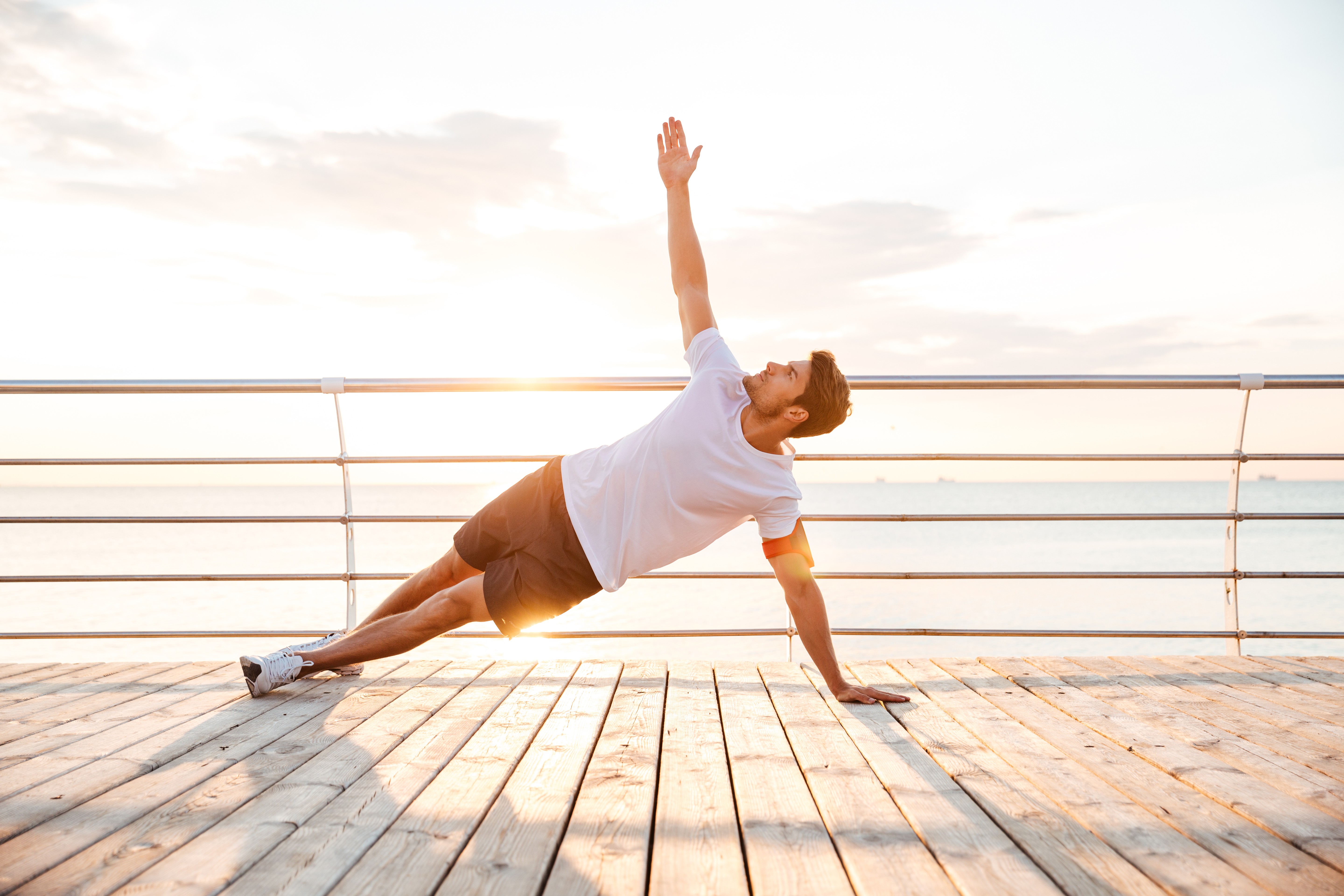 man doing yoga on a boardwalk