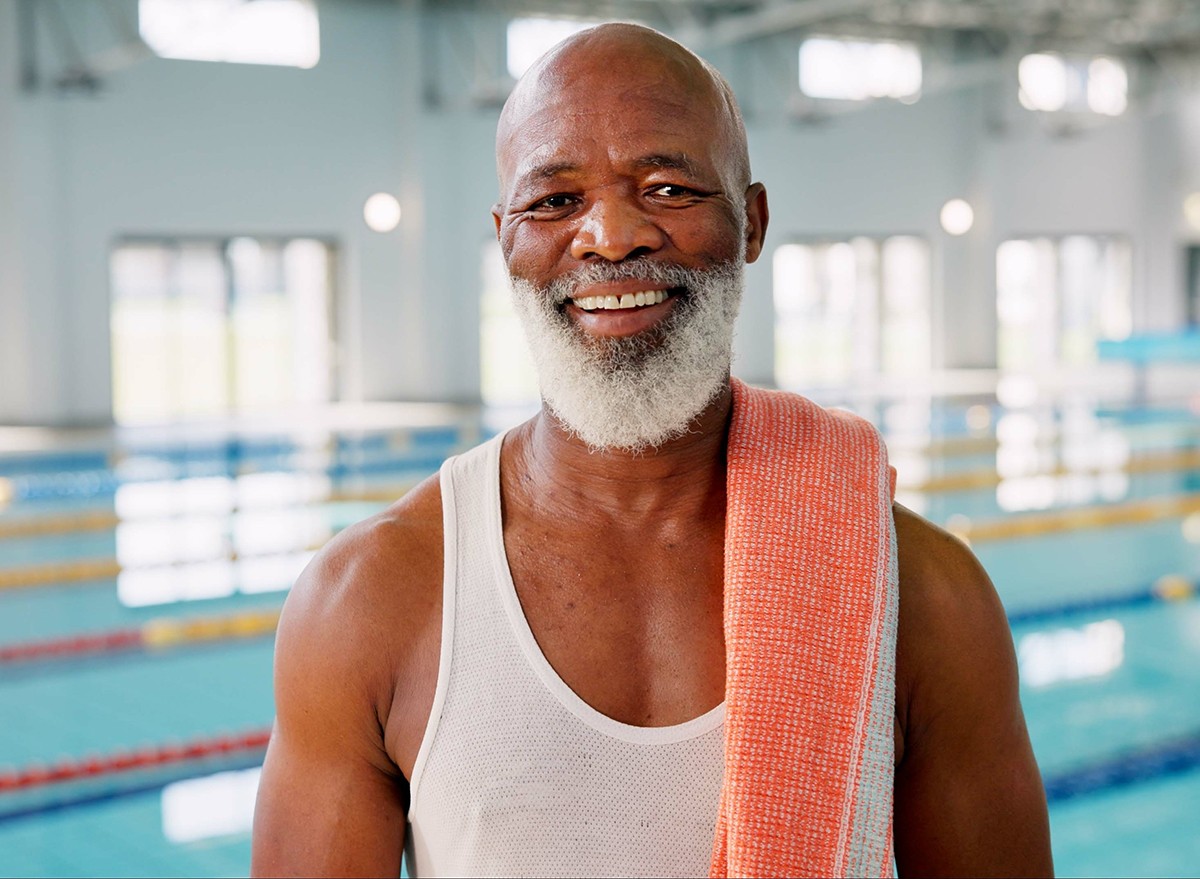 A smiling man standing next to a swimming pool