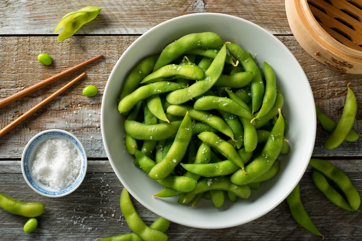Fresh steamed edamame sprinkled with sea salt on a rustic tabletop