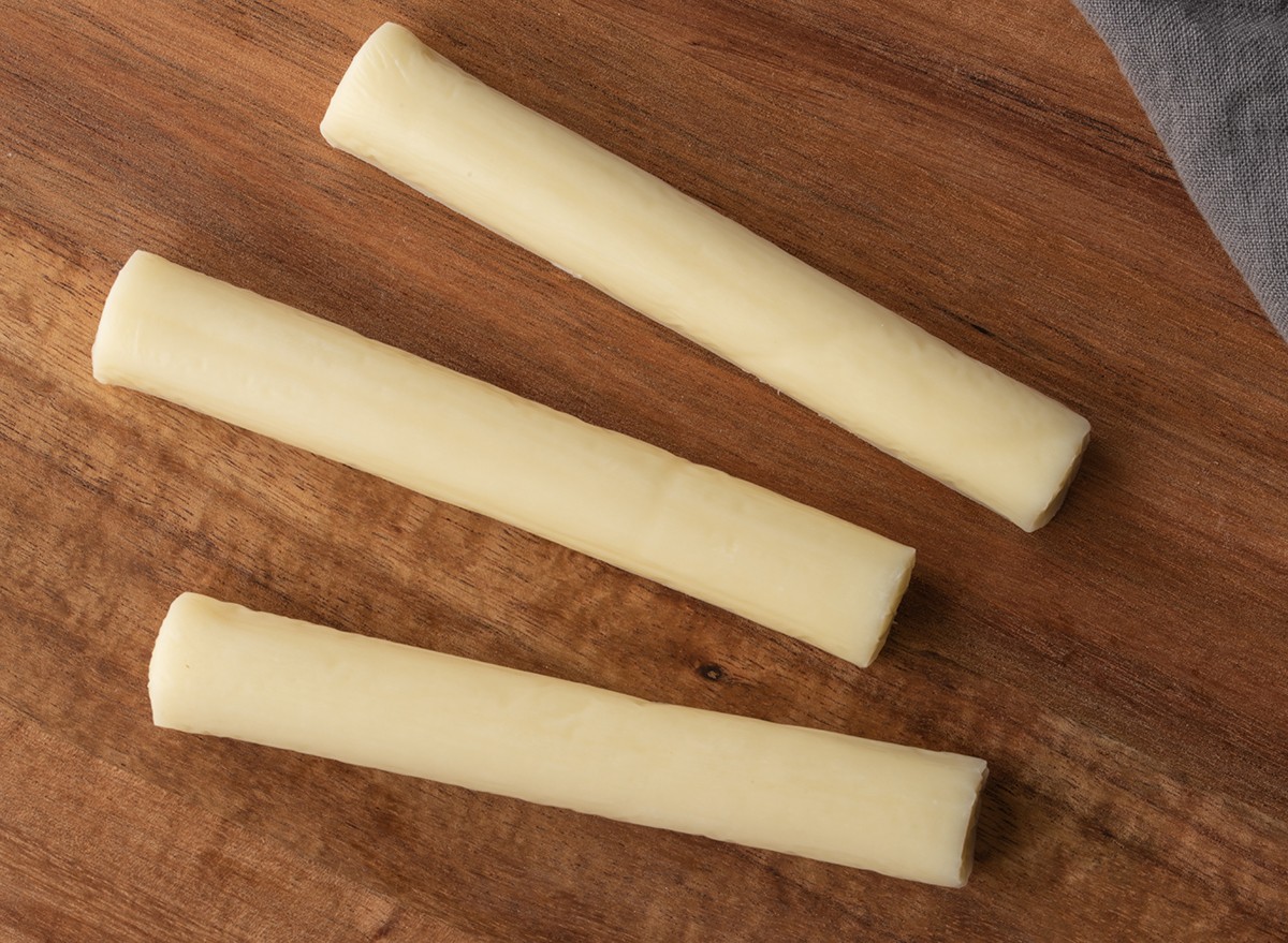 Three pieces of string cheese on a wooden cutting board