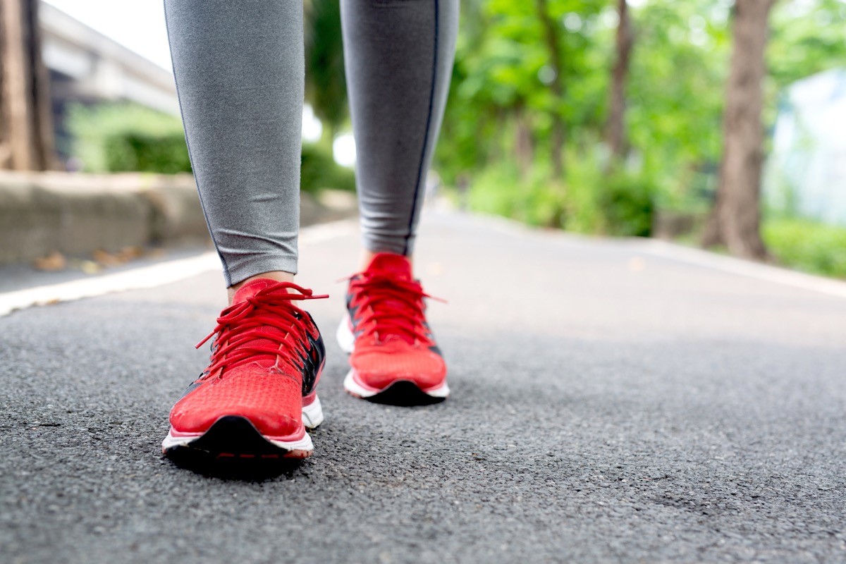 Person wearing red running shoes walking in park