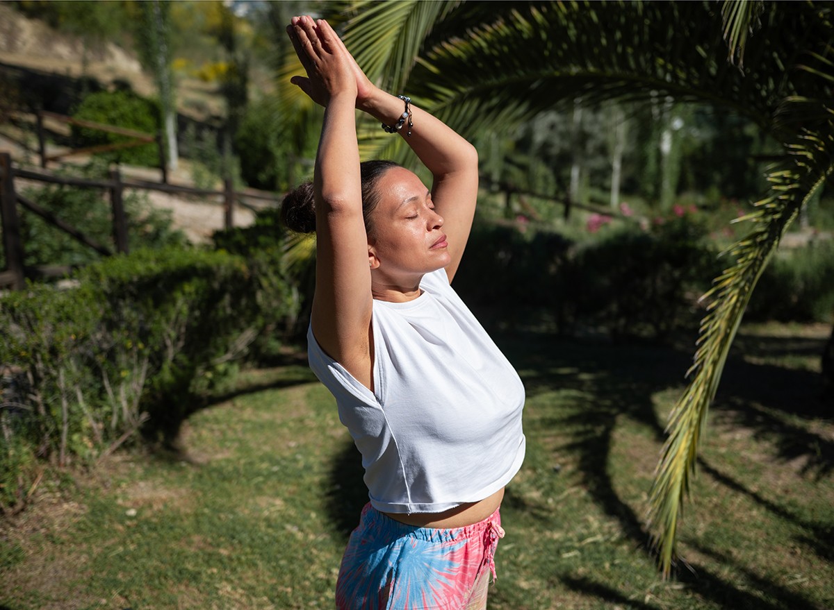 A woman with her arms above her head stretches and warms up